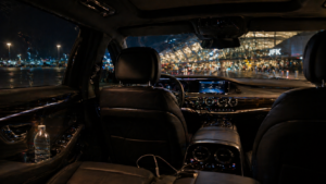 Luxury sedan interior with airport terminal visible at night for 247 NYC airport car service